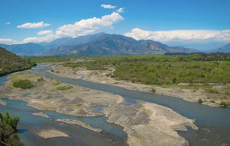 En la imagen, se logra apreciar una toma frontal del curso del río 
                            Aconcagua. Hay praderas y, al fondo, se observa la Cordillera
                            de Los Andes. 
                            