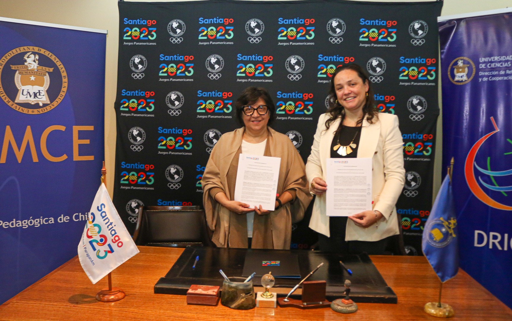 Gianna Cunazza y Elisa Araya sosteniendo el acuerdo firmado entre ambas instituciones.